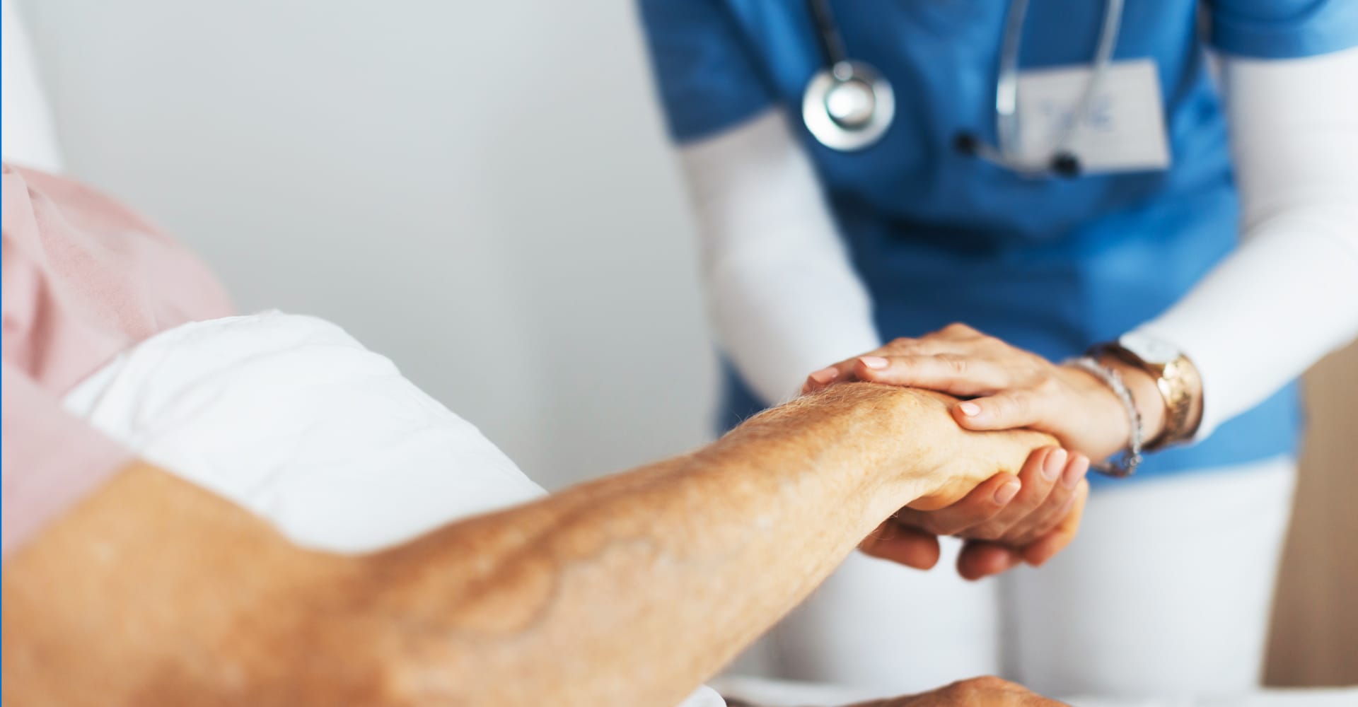 Close-up of a health care provider holding the hand of a senior patient